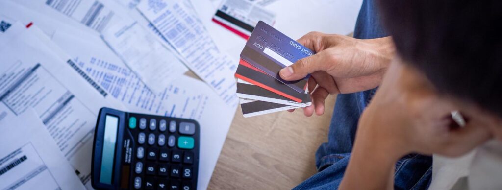man-holding-credit-cards-with-calculator-and-bill-statements-in-background