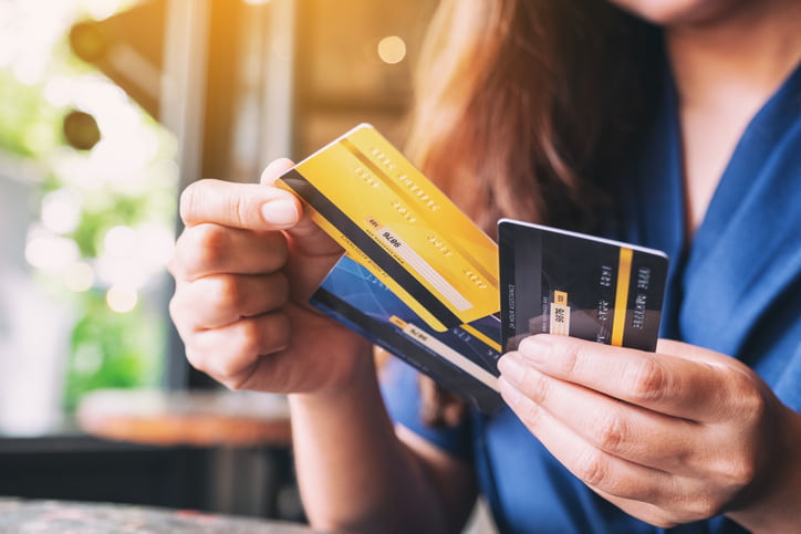 Person comparing three credit cards in a sunlit setting